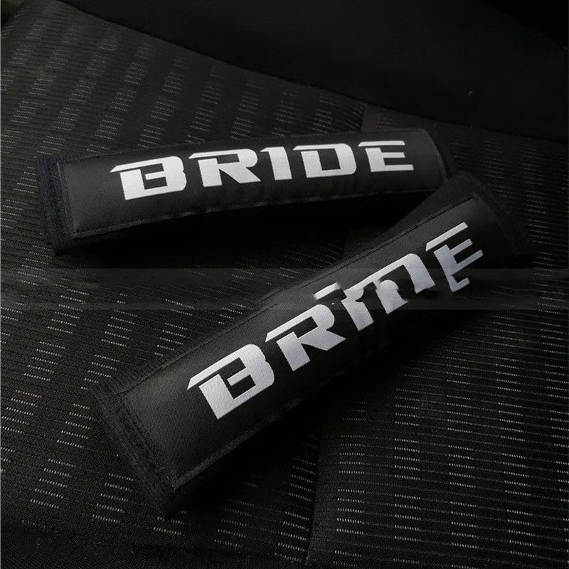 Pair of black car seat belt shoulder pads made from cotton and sponge cloth, showing size and embroidery detail.