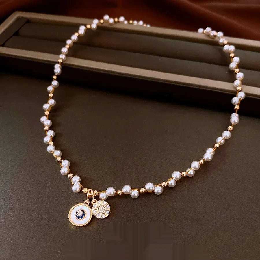 Gold electroplated clavicle necklace with round geometric pendant containing zircon inlay and imitation pearl centrepiece
