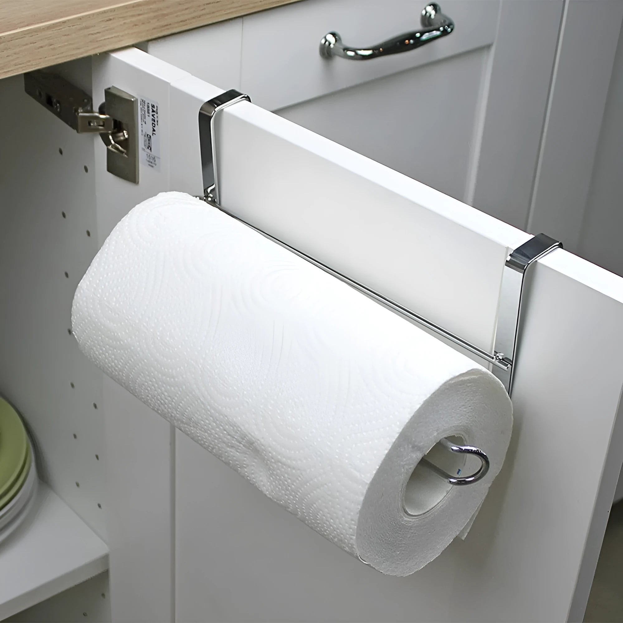 Silver stainless steel paper towel rack mounted on a white cabinet door.