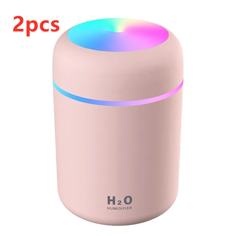 Pink USB mini humidifier with LED lights and water tank on desk