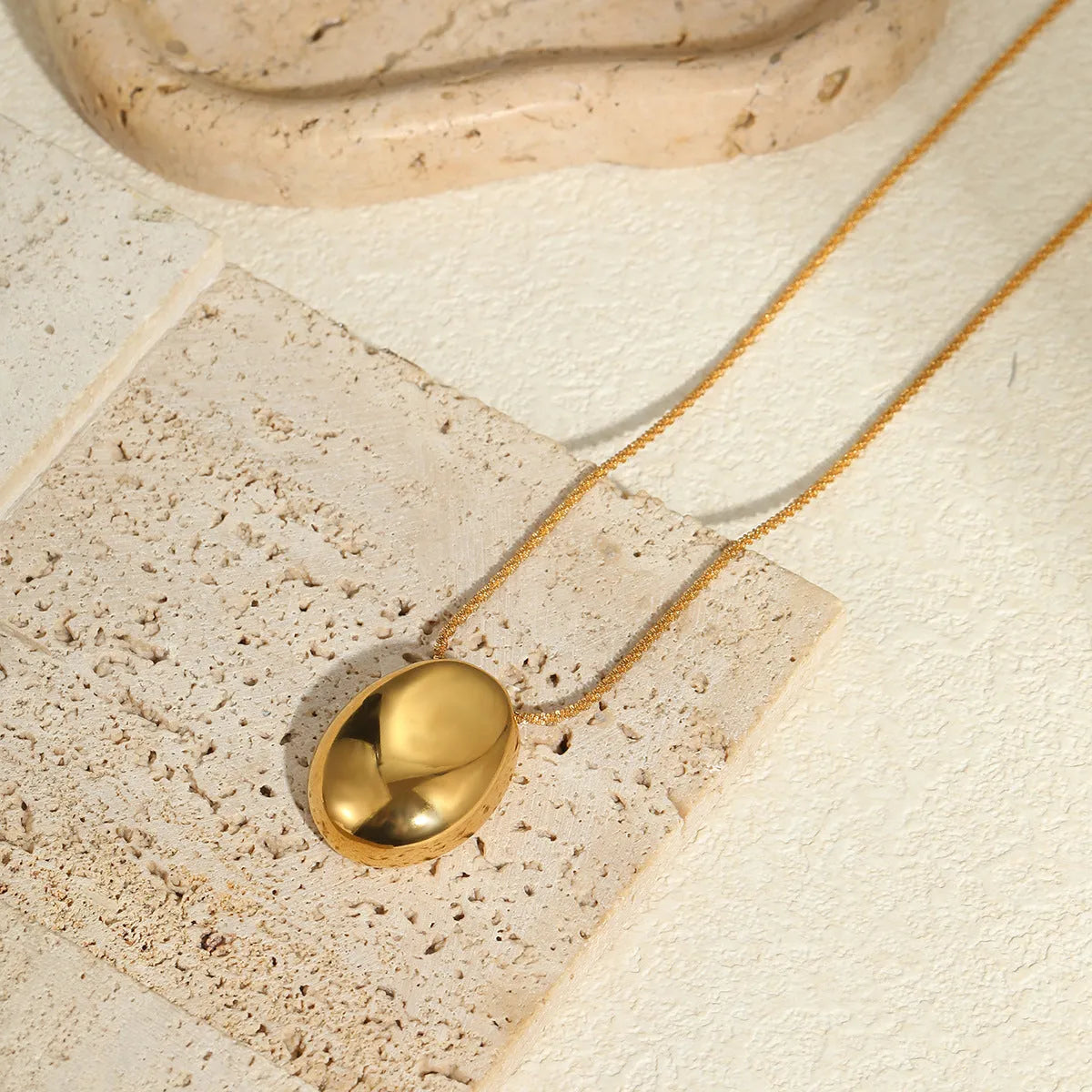 Gold geometric pendant necklace on a model, showing the adjustable chain length.