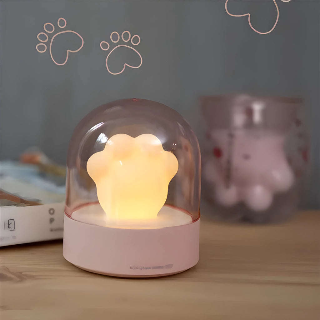 Grey or pink cat paw shaped USB rechargeable night light with music box function on a desk.