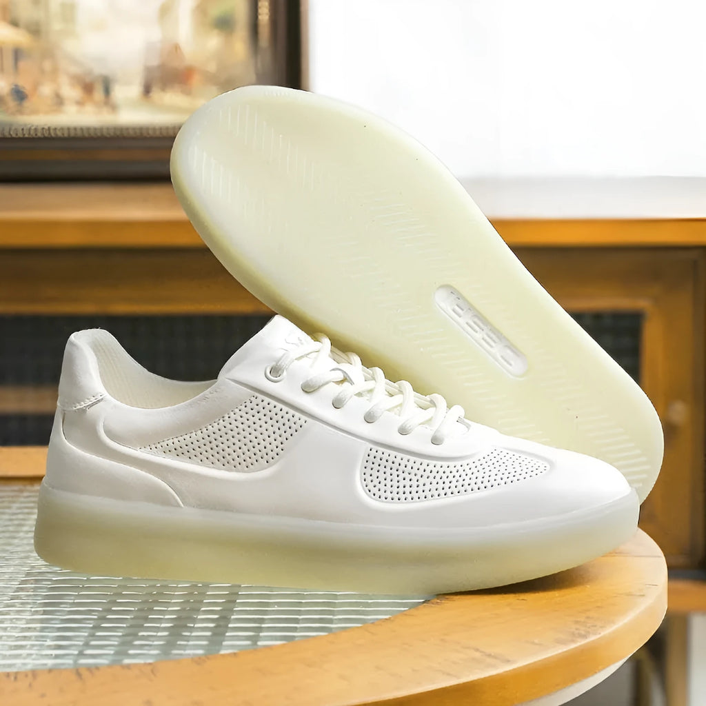 white perforated leather casual training shoes with rubber sole and front lace-up on flat surface