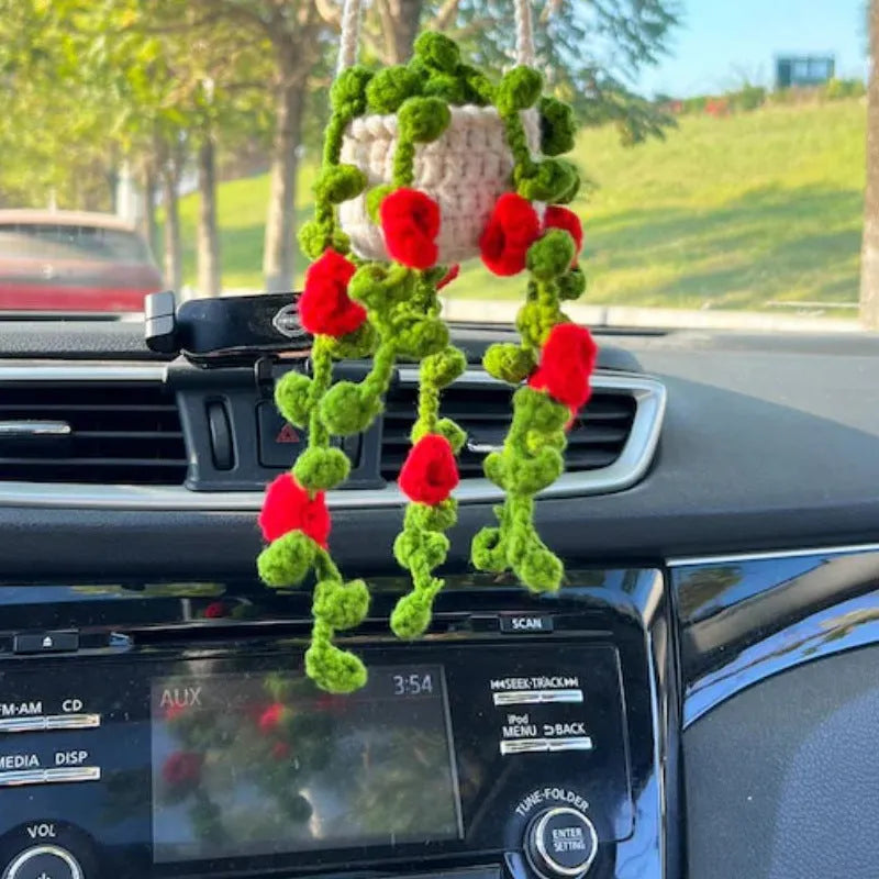 Green and white knitted wool car plant decoration with hanging rope on car dashboard
