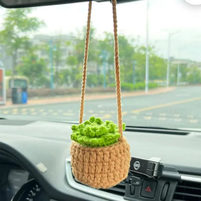 Green and white knitted wool car plant decoration with hanging rope on car dashboard