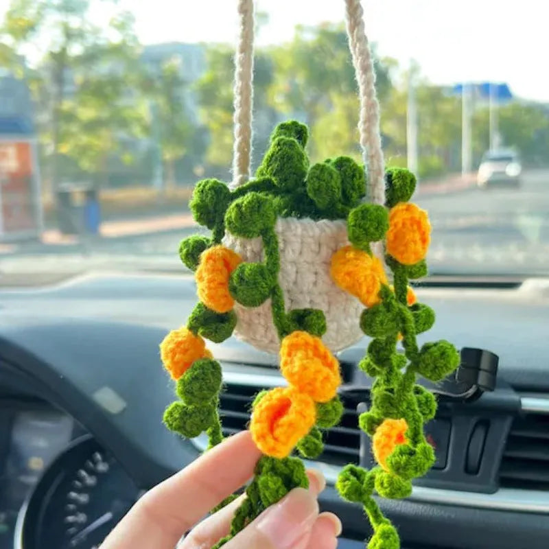 Green and white knitted wool car plant decoration with hanging rope on car dashboard