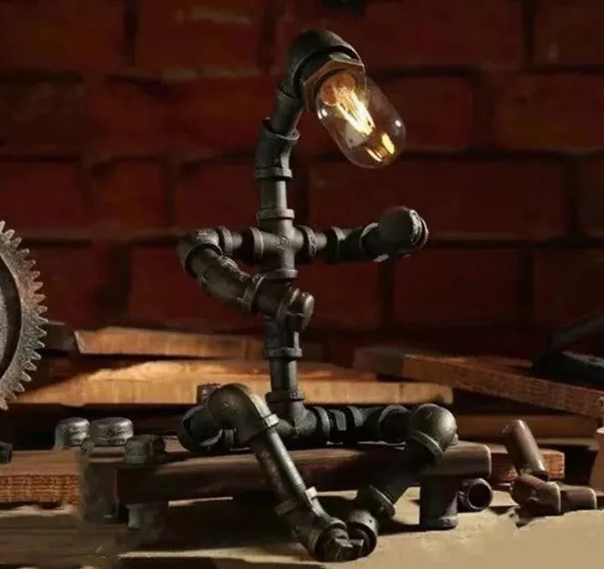 Green bronze vintage robot table lamp with industrial iron pipe design on wooden desk