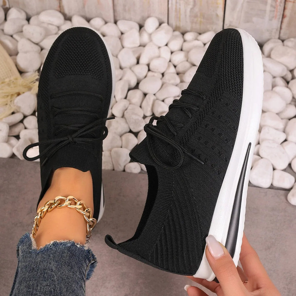 Women's black fly-knit casual sneakers with lace-up front and low-top design on a white background