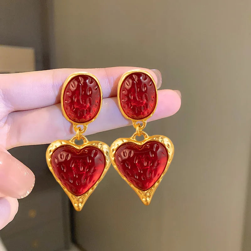 Oval-shaped love heart stud earrings with a pleated silver texture in purple, red, green, and yellow/white colours.