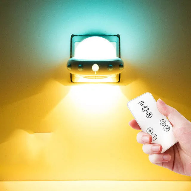 Blue UFO-shaped bedside night light with remote control on a table.