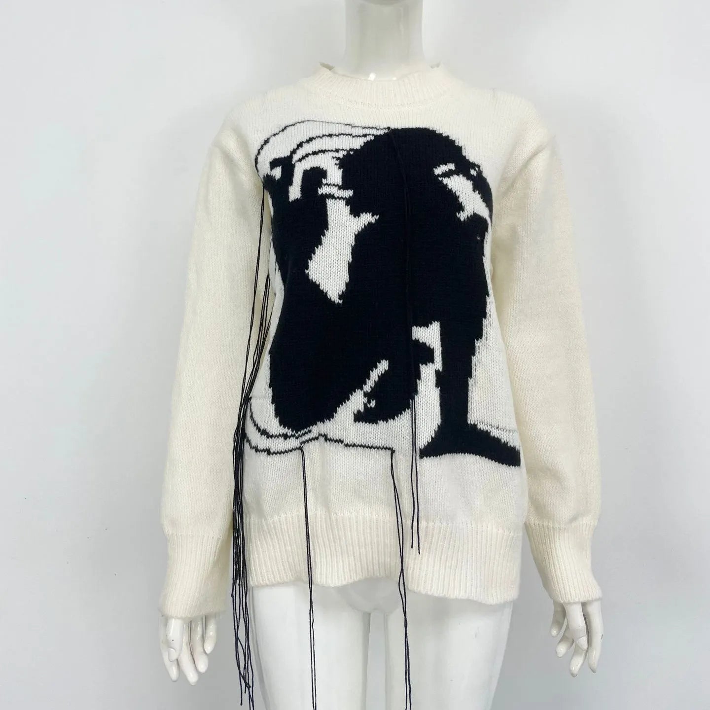 Grey women's alpaca wool pullover sweater with abstract pattern and tassel detailing on a hanger.