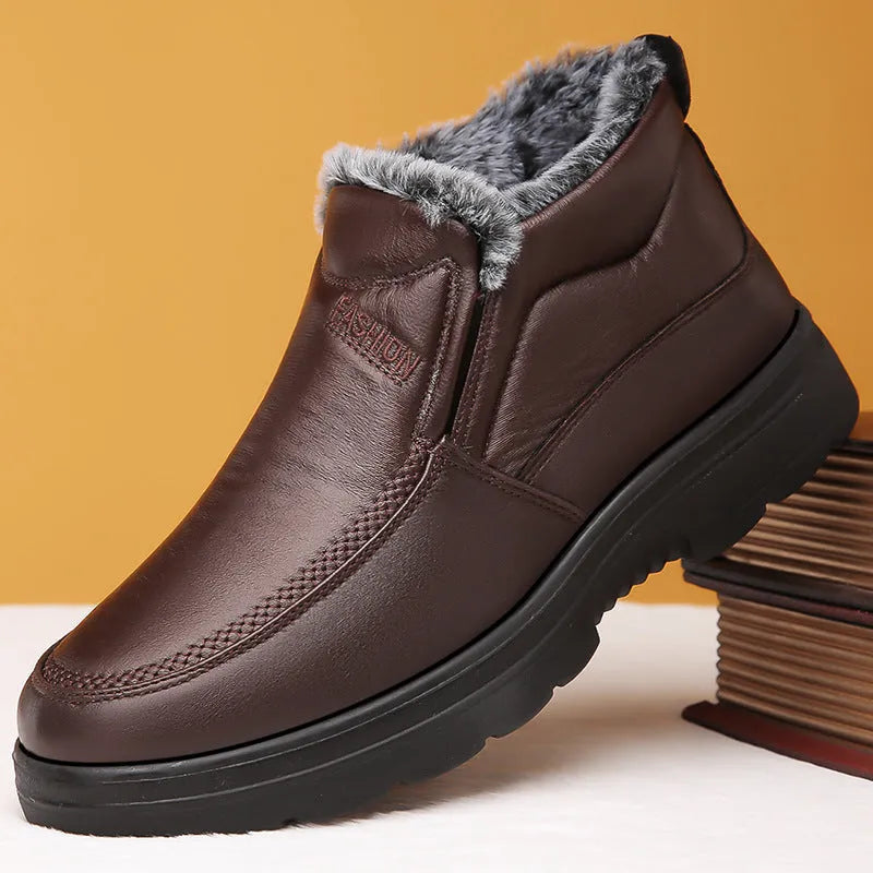Men's black and brown fleece-lined winter slip-on shoes with rubber soles on a wooden floor.