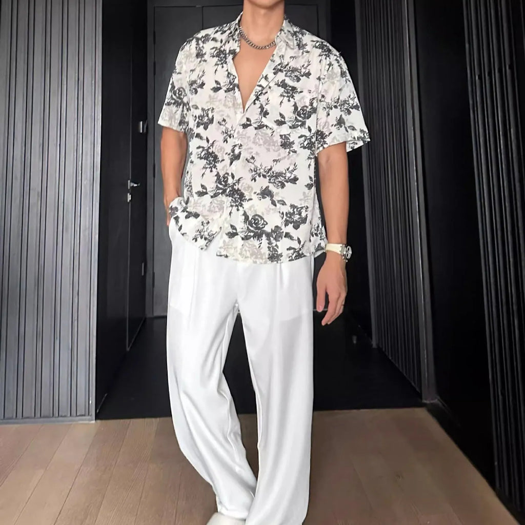 Man wearing a loose black floral print short sleeve casual shirt with a cardigan style open front.
