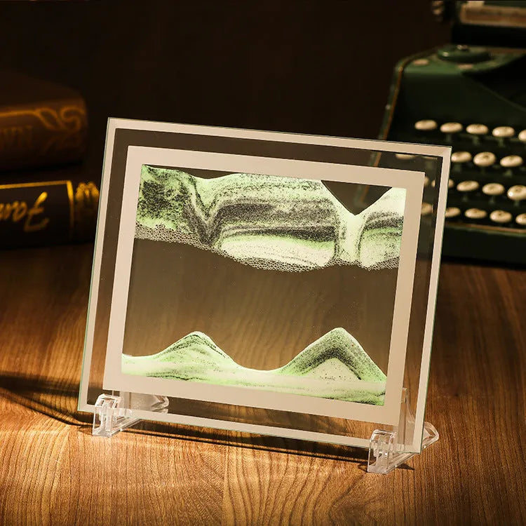 Glass quicksand painting ornament with geometric shape showing landscape sand art in black and white green colours.