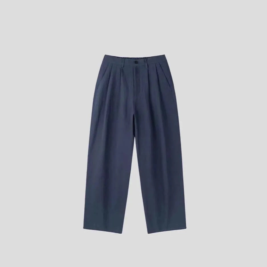 Men's lightweight apricot coloured wide-leg cotton linen trousers with a pencil leg opening on a hanger