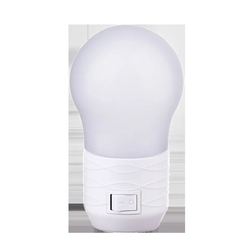 Plug-in bedside baby night light in white, blue, or pink shell with round design on a table
