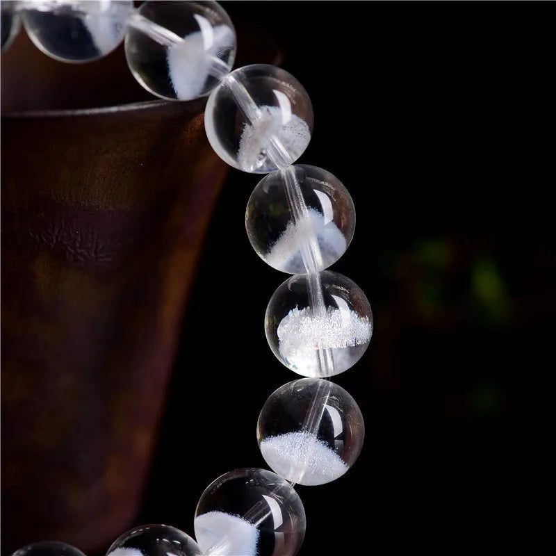 Women's white crystal ghost pyramid bracelet with Ruyi symbol on wrist, showing bead detail.