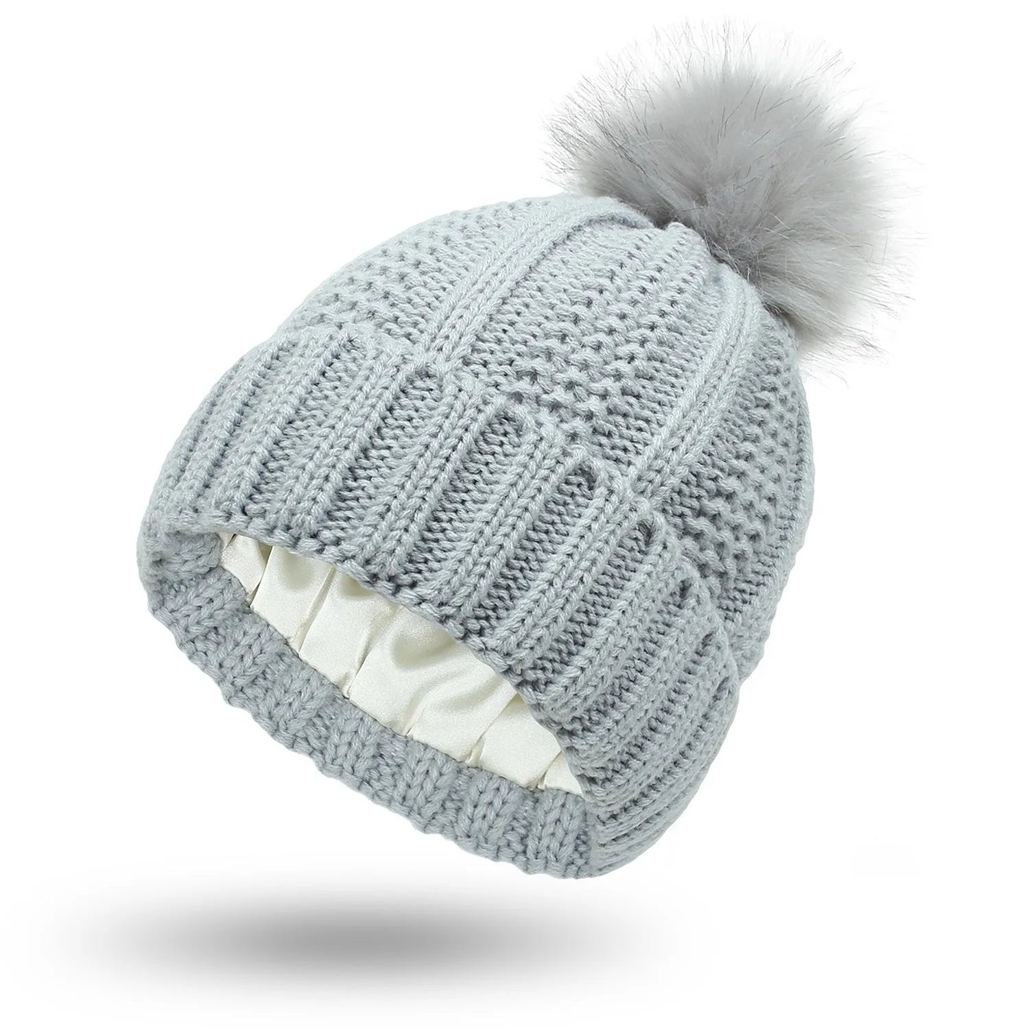 Woman wearing a light grey wool beanie with a faux fur pom pom and satin lining.