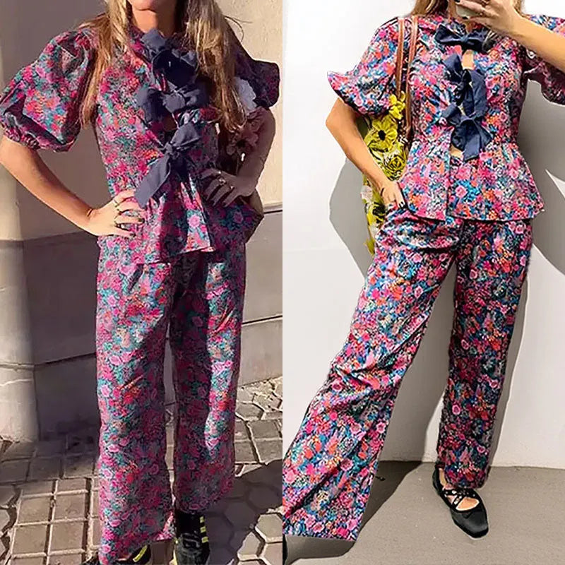 Floral print two-piece leisure suit with tie-neck blouse, puff sleeves, and long trousers.