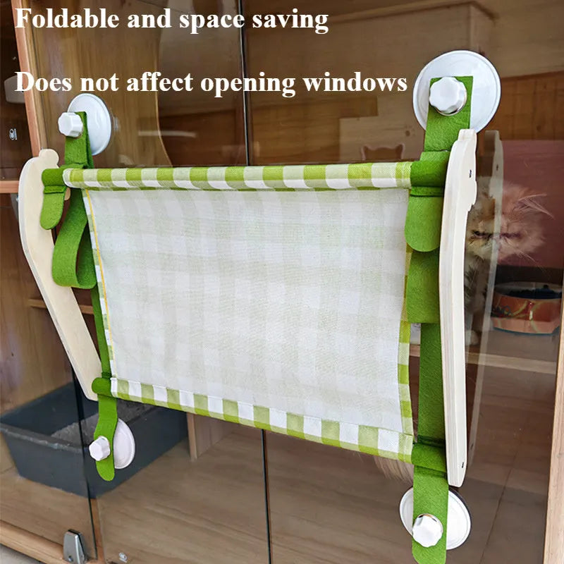 Pink wooden cat hammock with suction cups attached to a window, showing a cat resting on the linen fabric.