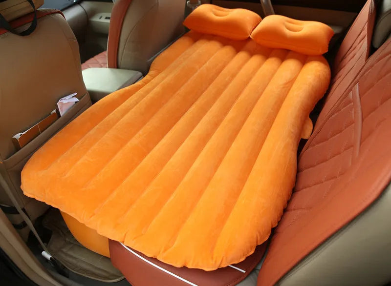 Inflatable car bed with flocked surface and two pillows, shown folded next to its storage bag.