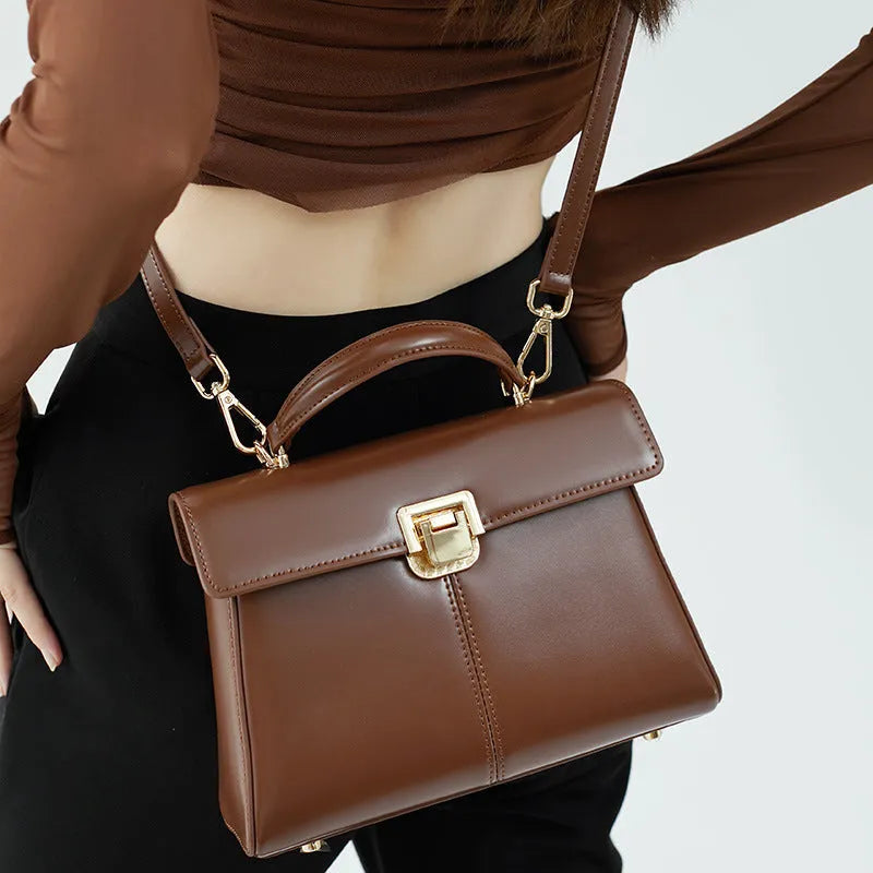 Black genuine vachette leather women's shoulder bag with clasp closure, showing square shape and adjustable strap.