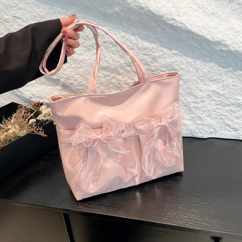 Black and pink college style bow tote bag with double straps and a front view.