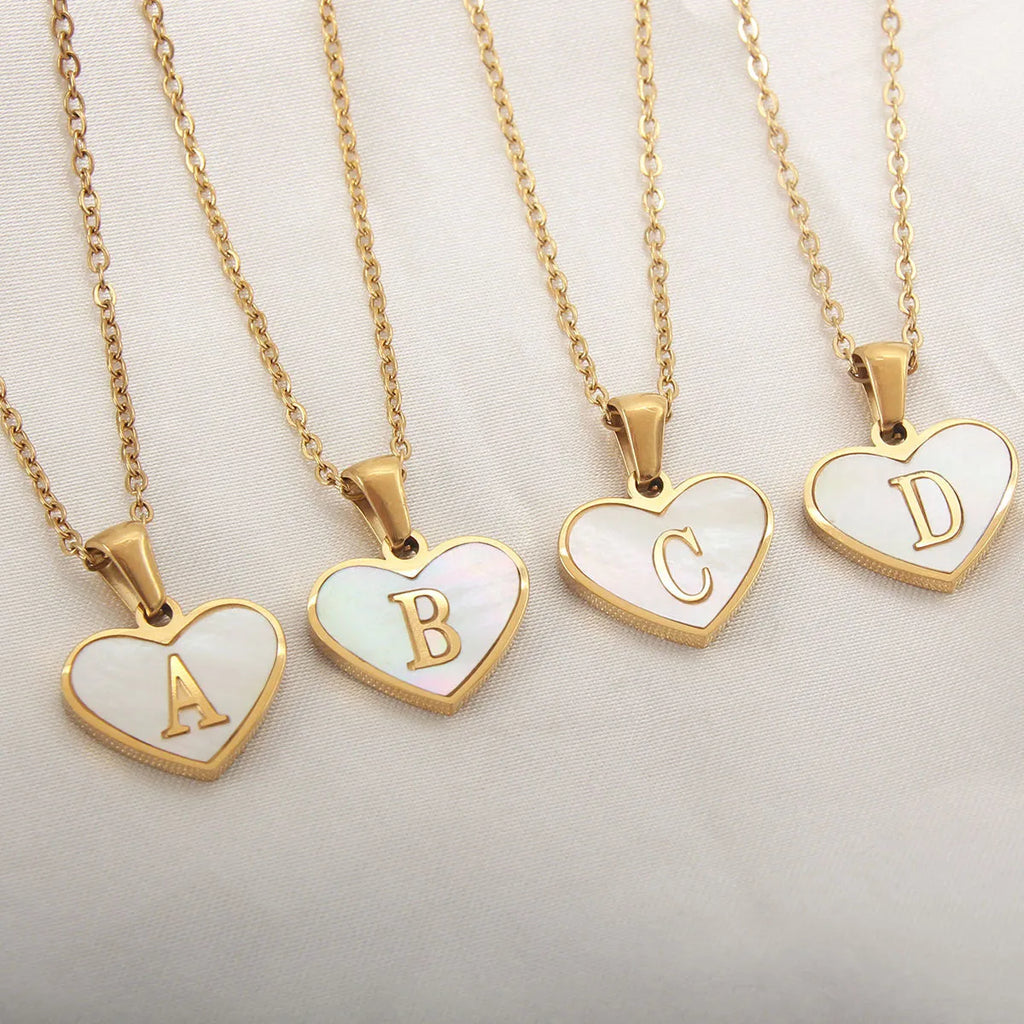 Gold-plated heart necklace with white shell pendant personalised with a letter, on an adjustable chain.