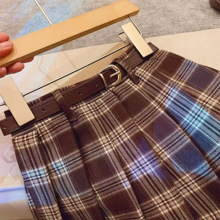 Girls red and black plaid pleated A-line skirt with a cotton lining, shown on a hanger.