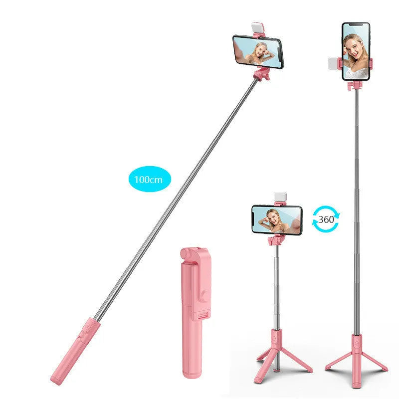 Black Bluetooth selfie stick tripod with phone holder, fill light, and remote control on a table.