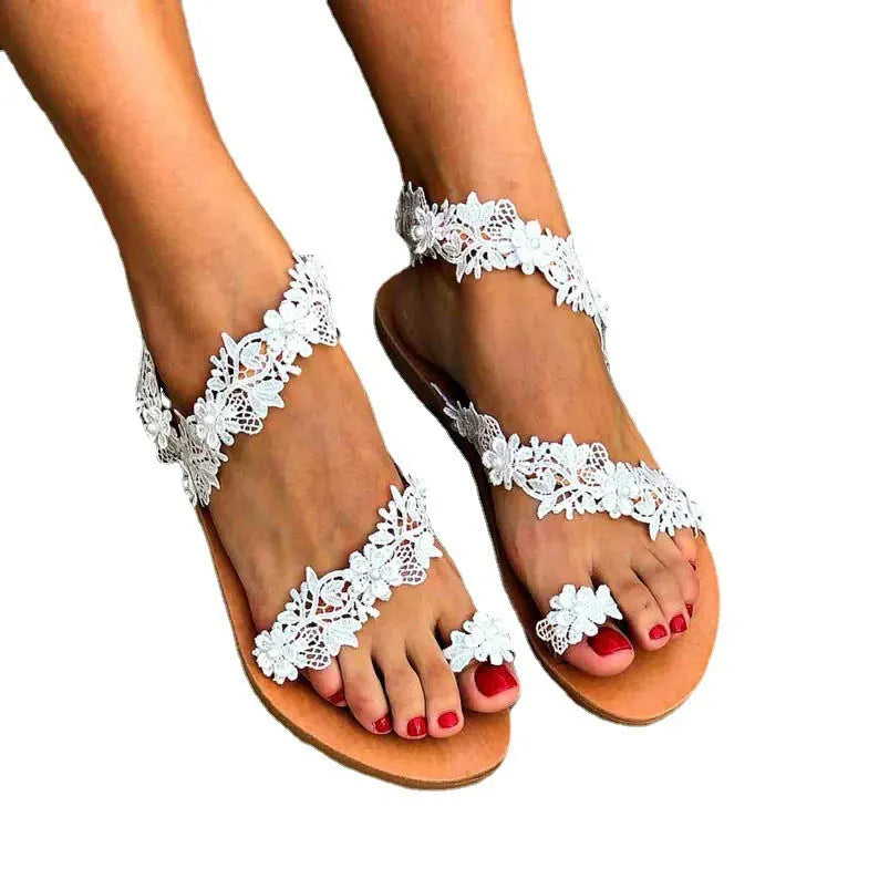 White women's flat sandals with rhinestone flower decoration on PU upper and rubber sole.