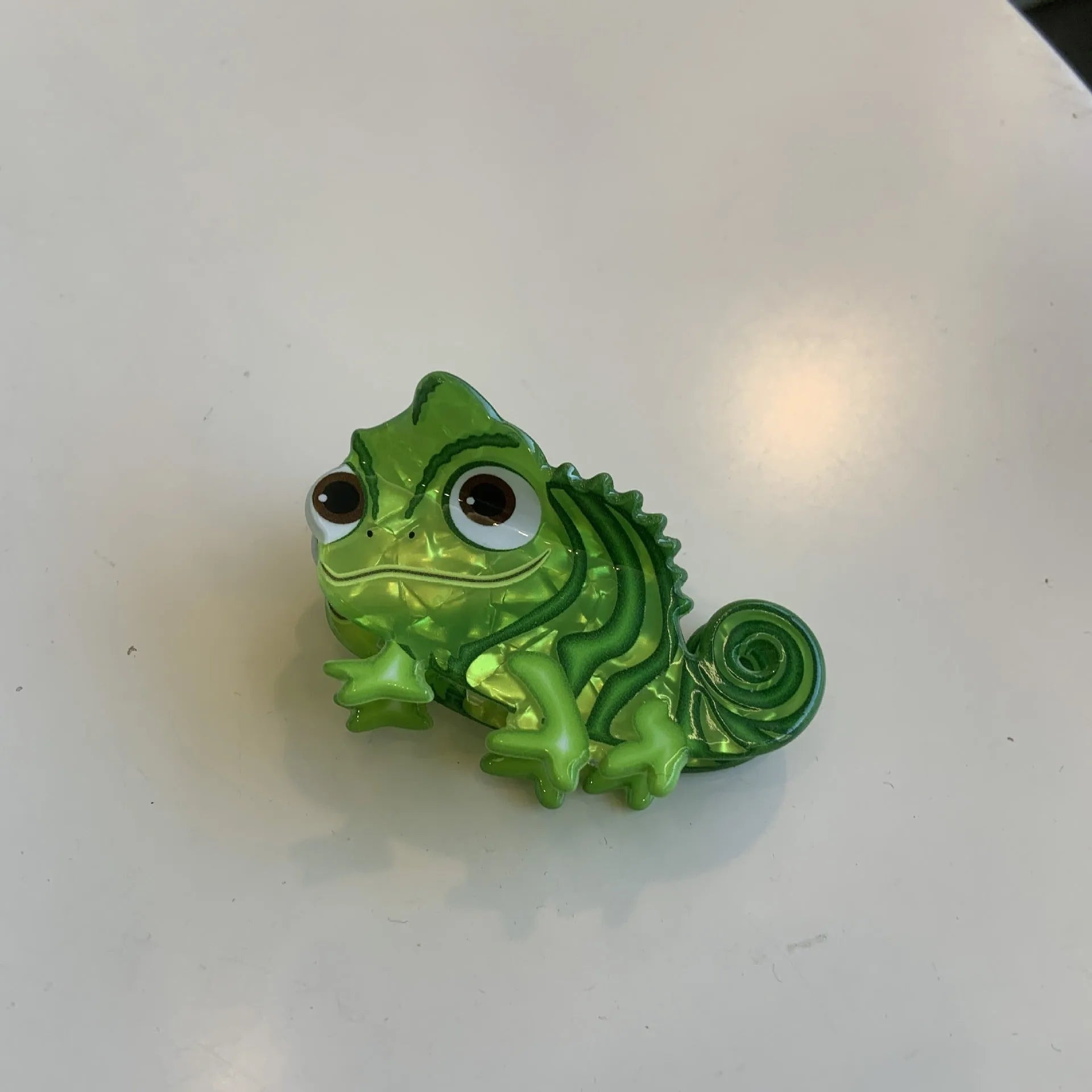 A colourful acrylic jaw clip hair grip featuring a detailed little dinosaur design.