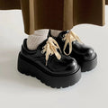 Matte black women's high-heel shoes with a thick rubber sole and lace-up buckle.