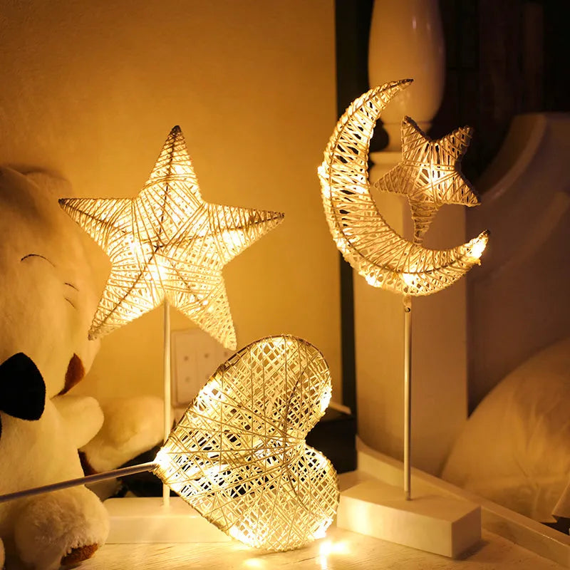 Rattan and copper wire LED table lamp in a star, heart, or moon shape on a wooden table.
