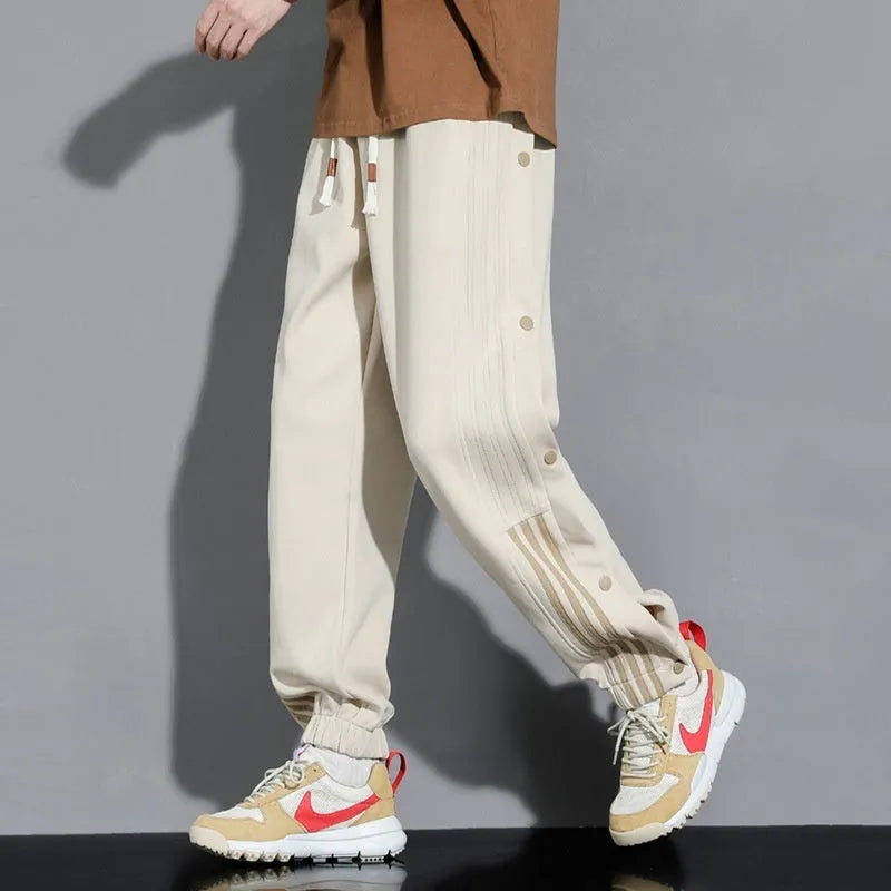 Man wearing loose grey cotton blend sweatpants with ankle ties and a drawstring waist.
