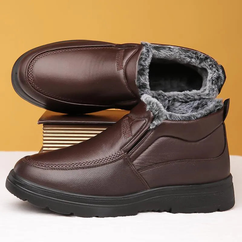 Men's black and brown fleece-lined winter slip-on shoes with rubber soles on a wooden floor.