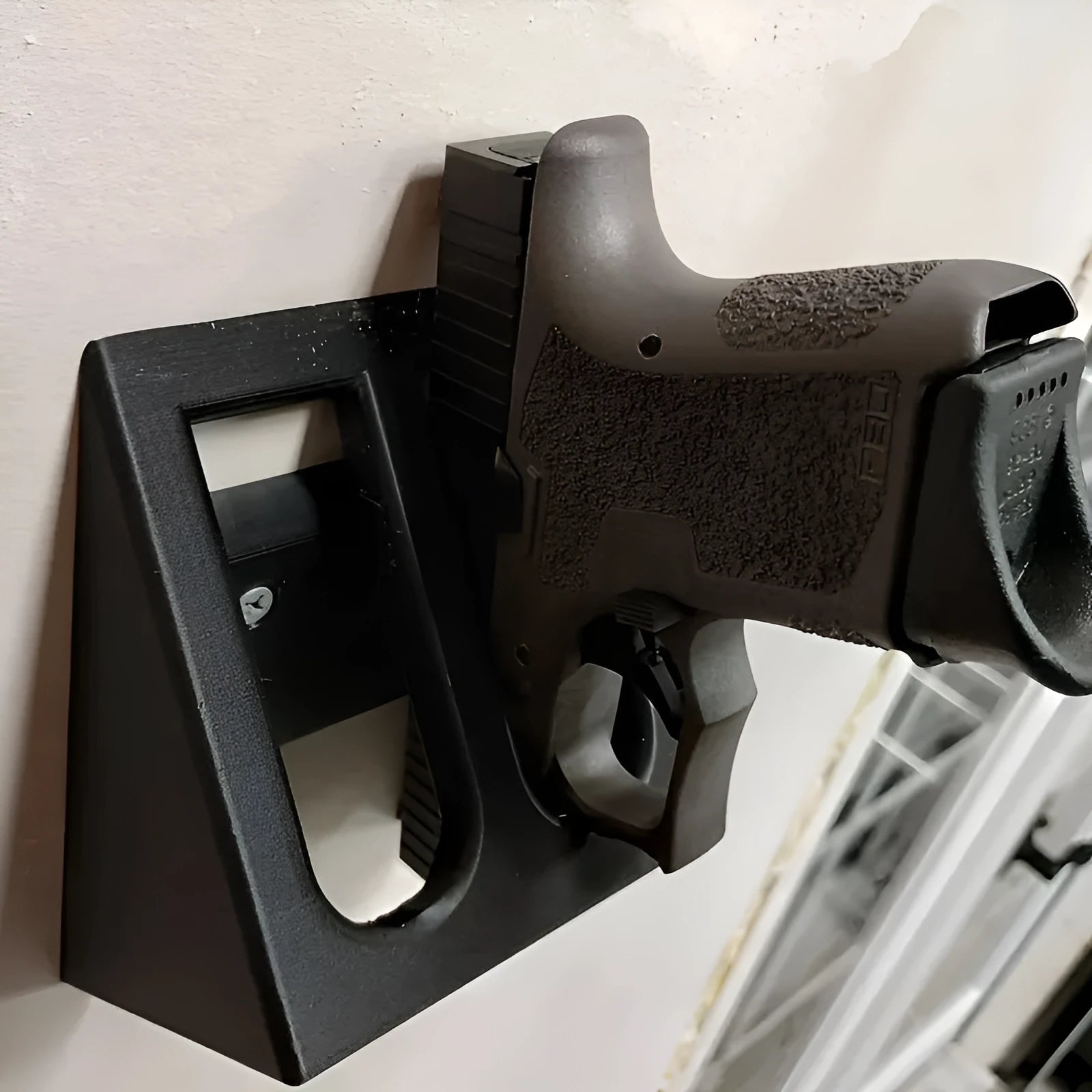 Black punk-style plastic pistol display stand on a surface, showing its compact size and cradle design.