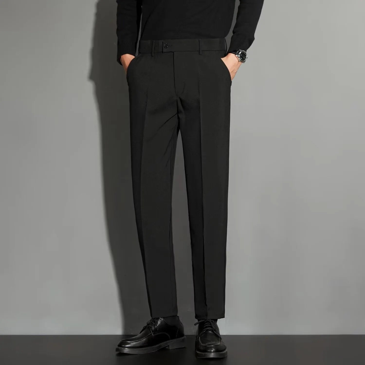 Man wearing straight leg ankle-length suit trousers in a light colour, showing the drape of the fabric.
