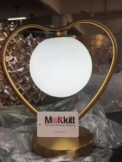 White heart shaped table lamp with a flexible metal arm and warm LED light on a wooden surface.