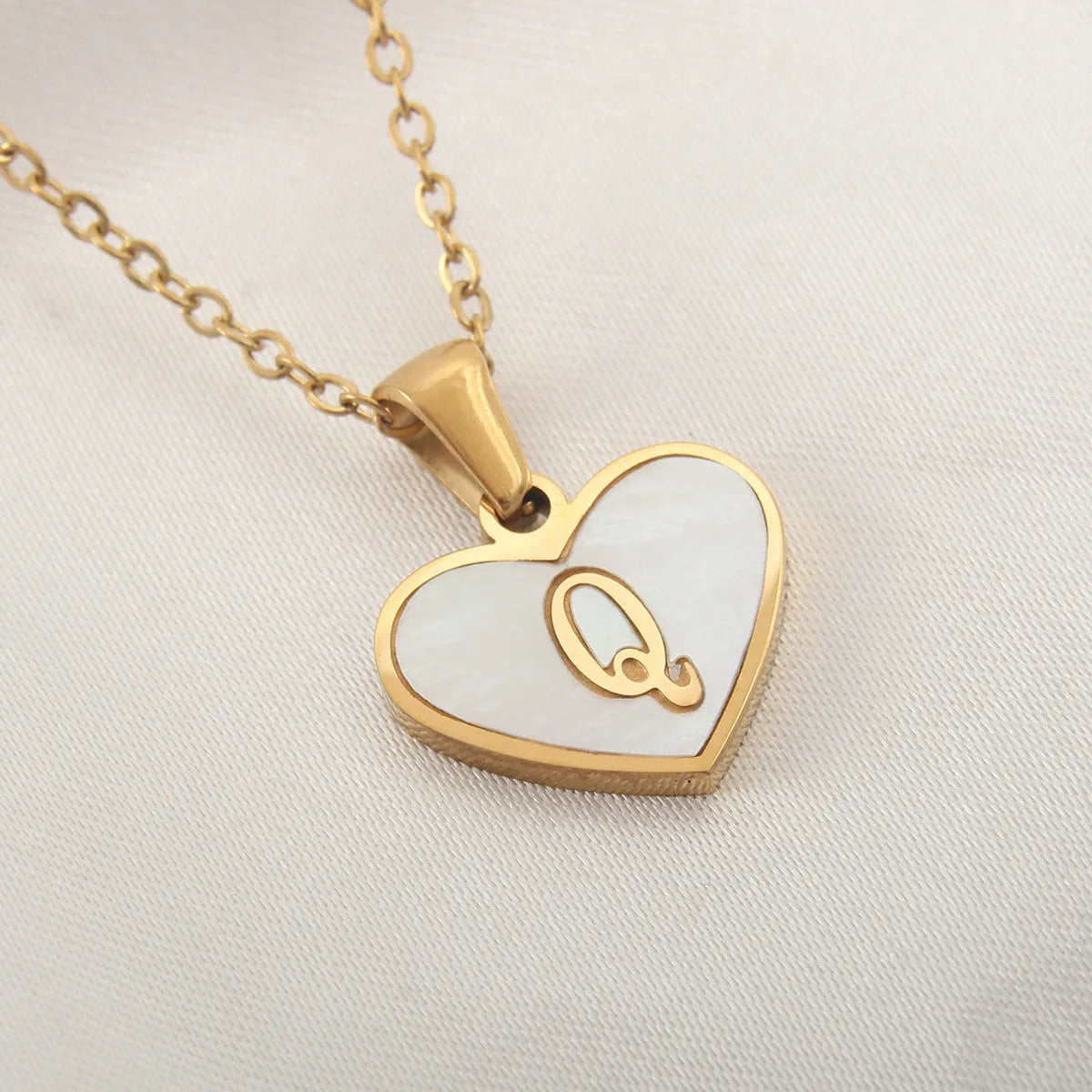 Gold-plated heart necklace with white shell pendant personalised with a letter, on an adjustable chain.