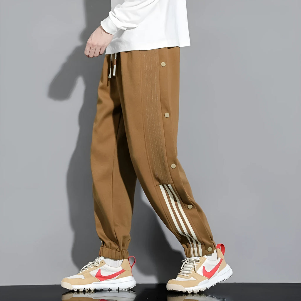 Man wearing loose grey cotton blend sweatpants with ankle ties and a drawstring waist.