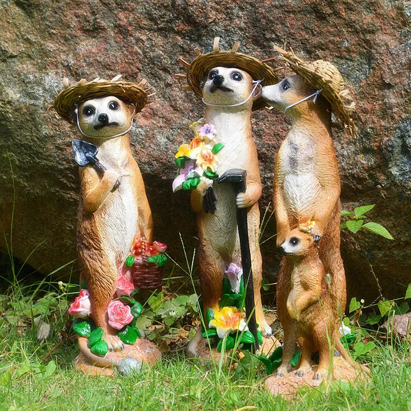 Three small straw hat mongoose garden ornaments: one with a baby, one holding a rake, one holding a shovel.