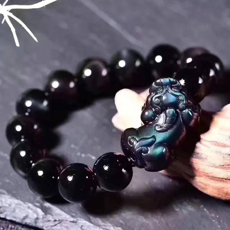 Natural obsidian stone bead bracelet with adjustable black cord on a wrist.