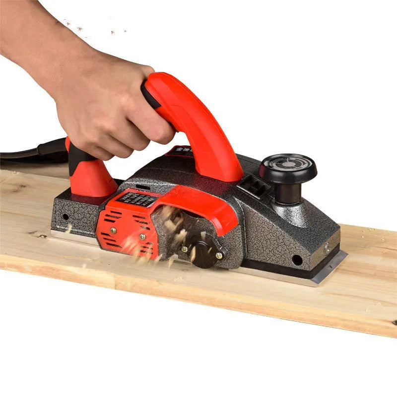 Red electric wood planer with aluminium housing showing 82mm planing width and power specifications