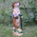 Three small straw hat mongoose garden ornaments: one with a baby, one holding a rake, one holding a shovel.