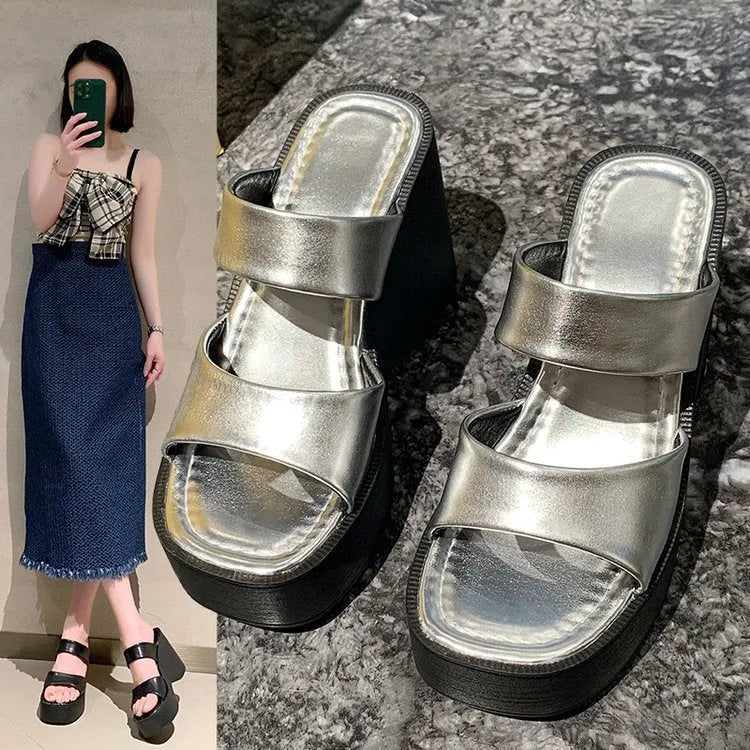 Women's black platform wedge slippers with a square toe design on a white background.