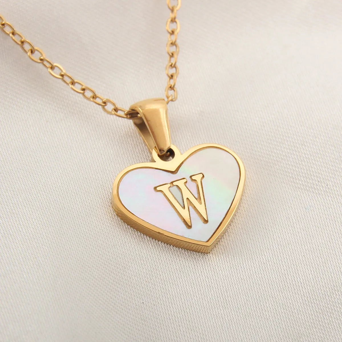 Gold-plated heart necklace with white shell pendant personalised with a letter, on an adjustable chain.