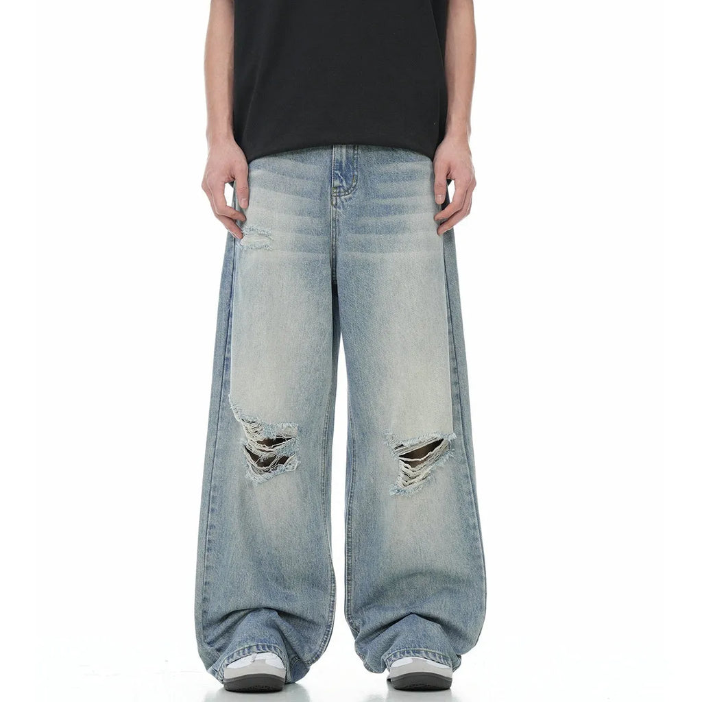Man wearing blue straight-leg jeans with ripped detailing and an adjustable waistband.