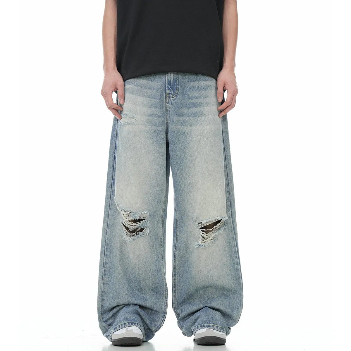 Man wearing blue straight-leg jeans with ripped detailing and an adjustable waistband.