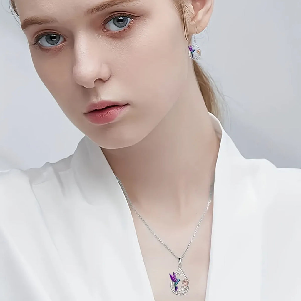 White electroplated copper hummingbird necklace and earring set with animal motifs on a neutral background